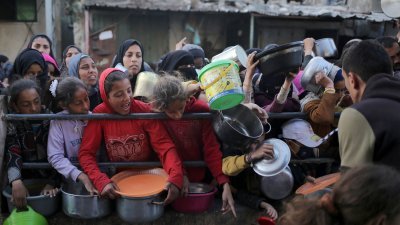 在加沙地带南部拉法，穆斯林斋戒月的第一天，流离失所的巴勒斯坦人周一在开斋前等候领取慈善机构捐赠的食物。（图取自法新社）