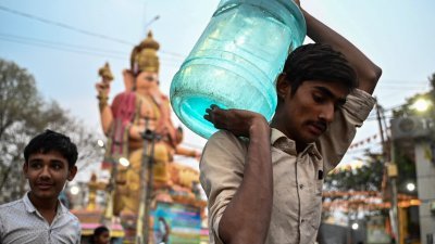 印度卡纳塔克邦首府班加罗尔的民众，周四用瓶子装取食用水，再抬回家。（图取自法新社）