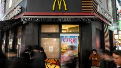 麦当劳系统周五发生全球大当机，日本大多数门市当天暂停现场和线上订单。图为人们站在东京新桥区一家暂时关闭的麦当劳餐厅前。（图取自法新社）