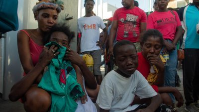 海地首都太子港郊区佩蒂翁维尔周一有十几人在街头遭帮派杀害，陷入悲伤和恐惧的民众坐在油站哭泣。（图取自法新社）