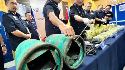 武吉安曼毒品罪案调查部总监许国振（左3）向媒体展示经过改装藏毒用途的煤气桶。