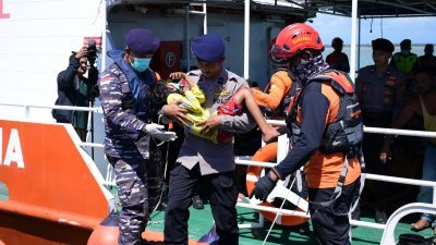 印尼警员抱著一名罗兴亚难民儿童，从灾难拯救组织（Basarnas）的船只上走下来。（图取自法新社）
