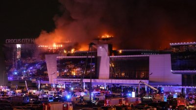 莫斯科近郊克拉斯诺戈尔斯克市的音乐厅发生严重枪击事件后，起火燃烧的音乐厅外看到紧急服务车辆赶到现场，浓烟升上半空。（图取自法新社）