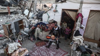 以色列和哈马斯的战斗仍在持续之际，在加沙南部拉法，有一户家庭成员在被以色列袭击摧毁的房屋废墟中准备享用斋月期间的早餐。（图取自法新社）