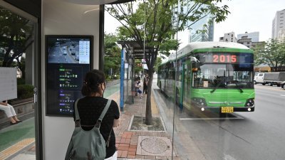 民众在韩国首尔市的一个公交亭等候公共巴士。（自法新社档案照）