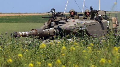 图为上周四，在以色列南部与加沙地带接壤的边境，一名以色列士兵在一辆坦克上打出手势，沿著与巴勒斯坦领土的边境行驶。（图取自法新社）