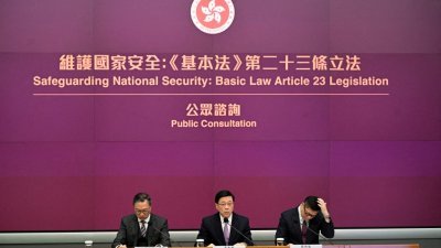 香港特首李家超（中）、律政司司长林定国（左）和保安局局长邓炳强（右）1月30日在香港政府总部就《基本法》第23条立法举行记者会。（法新社档案照）