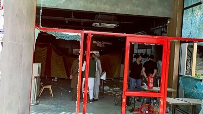 在巴控克什米尔地区东北部城镇米尔普尔，安全人员正在检查被纵火焚烧的美国快餐连锁店肯德基餐厅。（图取自法新社）