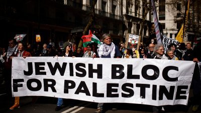 周六在英国伦敦市中心举行的抗议活动中，亲巴勒斯坦的支持者举著横幅游行呼吁停火。（图取自法新社）