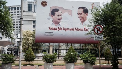 在雅加达国防部办公室前，展示了印尼总统佐科（右）和国防部长普拉博沃肖像的广告看板。（图取自法新社）