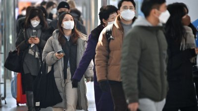 2022年2月18日，戴著口罩的人们走过首尔的火车站。（图取自法新社档案照）