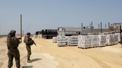以色列士兵周三在加沙地带北部的拜特哈嫩，监督人道援助物资透过以色列控制的埃雷兹码头，从约旦运送到加沙的行动。（图取自法新社）