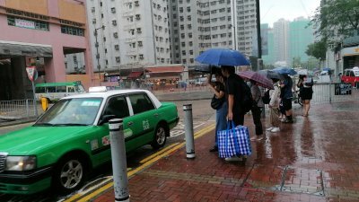 香港周六出现暴雨天气，市民冒雨出行。（图取自香港中通社）