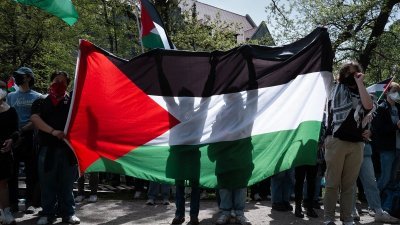 美国芝加哥大学校园内，亲巴勒斯坦示威者周五在营地高举巴勒斯坦国旗。（图取自法新社）