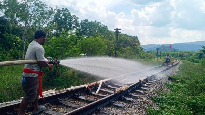 泰国南部洛坤府一条铁轨上个月底热到变形，工人向铁轨喷水降温。（图取自泰国国家铁路局/法新社）