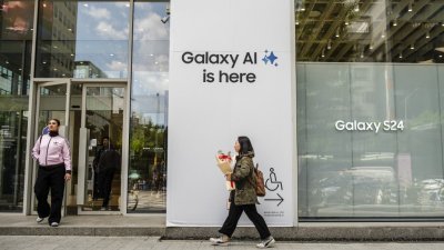 图为韩国一名行人走出首尔一家三星专卖店，店外广告标语写著“Galaxy AI就在这里”。（图取自法新社）