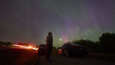 加拿大安大略省伦敦市当地时间周五晚出现了绚丽的极光，民众将车子停在路边，观赏这难得的天文景象。（图取自法新社）