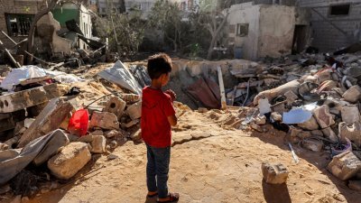 加沙地带南部拉法上周三一栋建筑遭到以色列轰炸，一名孩子站在炸弹投下的撞击坑旁。（图取自法新社）
