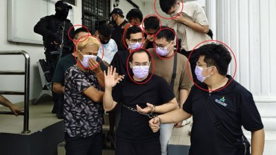 8名华裔被告面控后，在警方严密押送下走向警车。