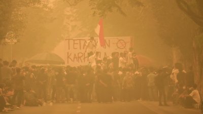 示威者周五在浓重的烟霾之中，聚集在印尼中加里曼丹省帕朗卡拉亚的省长办公室外示威，抗议野火问题并要求采取应对行动。（图取自法新社）