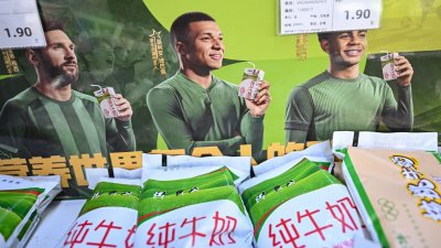 周三在中国首都北京市一家超市可见，中国乳制品品牌蒙牛的促销活动，仍然可见印有法国足球明星姆巴佩（中）肖像的宣传板。（图取自法新社）