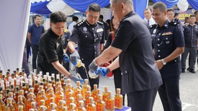 蔡国年（左二）率领警官及副检察司，将充公洋酒倒入销毁桶，完成销毁程序。（图由警方提供）