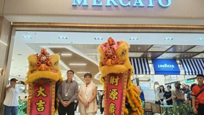 阮建达（左起）与Linda Phang在开幕仪式上与舞狮合影，庆祝新店正式开业。