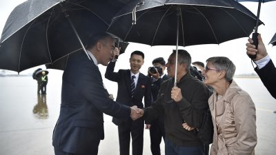 周四，瑞士外交部长卡西斯（中）及其妻子宝拉（右）抵达朝鲜平壤国际机场时，受到朝鲜官员迎接。（图取自法新社）

