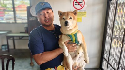 周本兴抱著事发当晚同车的爱犬。所幸人狗均安然无恙。(照片：周本兴提供)