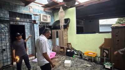 慕甘丹（右）巡视损失严重的单位，可见瓦片被掀起，住家单位屋顶“开天窗”。