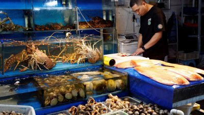 2023年8月24日，中国北京海鲜市场的一个海鲜摊位上，一名供应商正在处理北蛤。（图取自路透社档案照）
