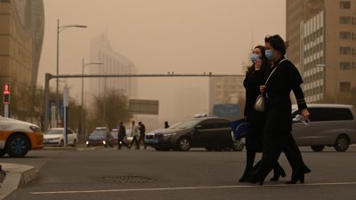 内蒙古呼和浩特市出现大风沙尘天气，市民周一在风沙中出行。（图取自中新社）