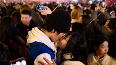 2024年1月1日，重庆解放碑步行街，不少市民、游客自发相聚于此，聆听跨年钟声、放飞“心愿气球”，共同迎接2024年的到来。图为现场拥吻的青年。（图取自中新社） 