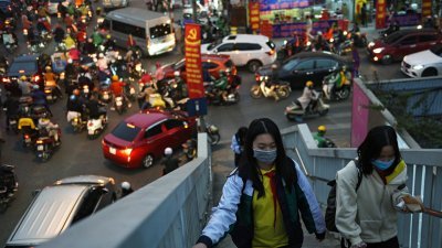 2021年1月29日越南爆发新冠肺炎疫情期间，戴著口罩的女学生们走在河内的天桥上。（图取自路透社档案照）