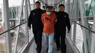 身穿橘色T恤的中国男子在新加坡落网后，被遣返回中国。 （取自网路）