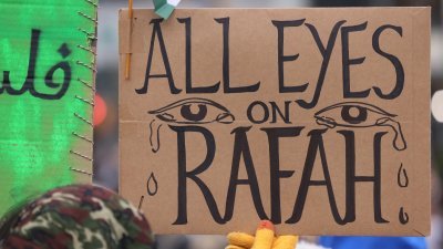 人们周日聚集在美国纽约市联合广场举行，呼吁以色列停止进攻加沙南部城市拉法，其中一人举著标语牌，写著“所有目光都在拉法”。（图取自法新社）