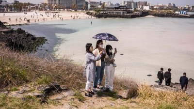 2022年4月22日，一群游客在济州岛济州市的Hamdeok海滩附近拍照。（图取自法新社档案照）
